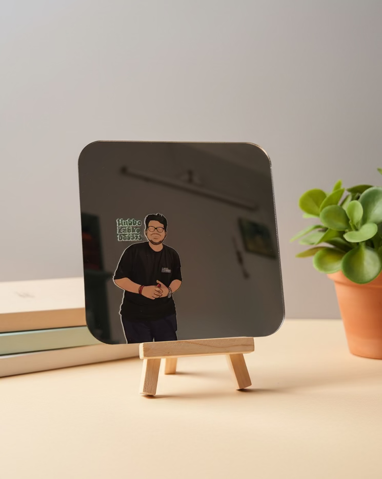 Small mirror on a stand with a reflection of a person wearing glasses, placed on a green cutting mat.
