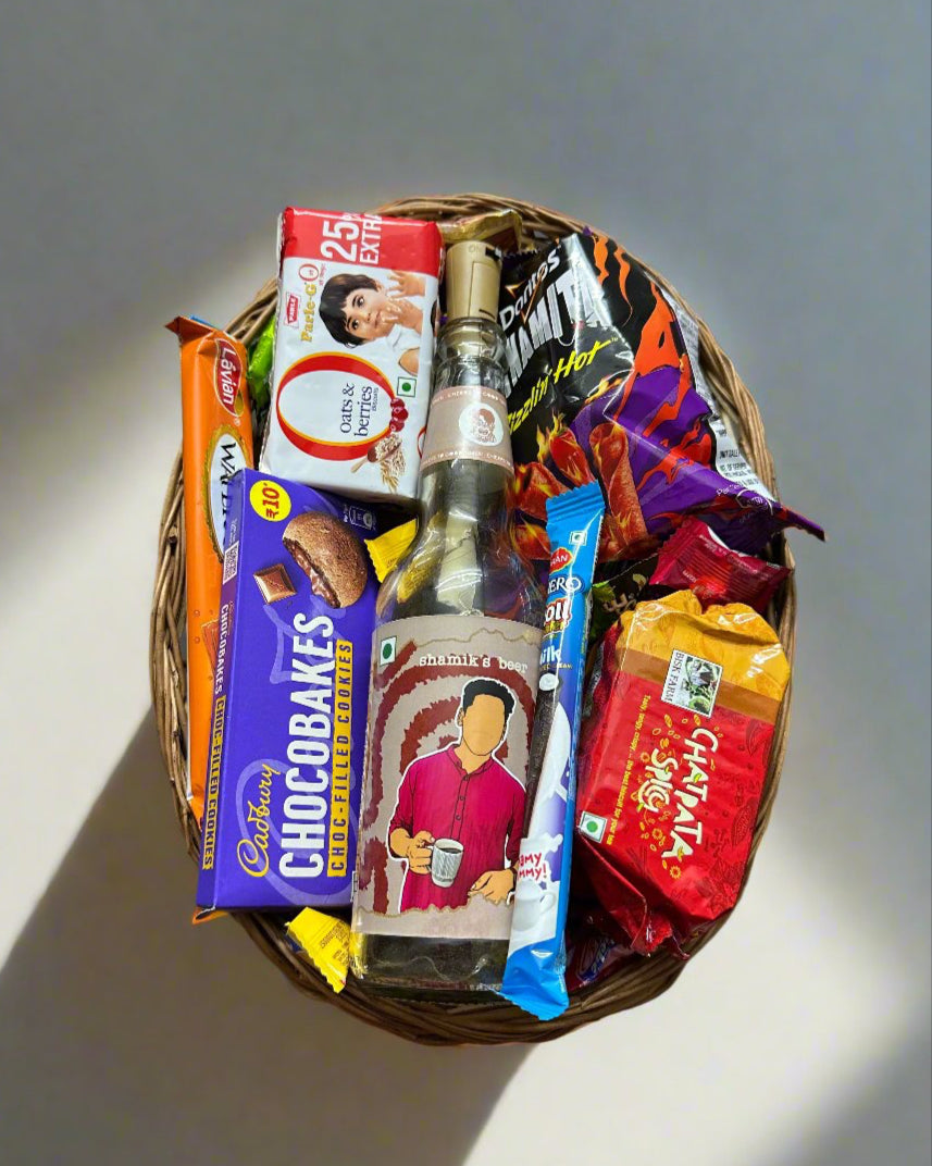 Personalized DopaMean bottle with LED light, surrounded by an assortment of delicious snacks, including chocolates, chips, and wafers, presented in a handcrafted cane basket.